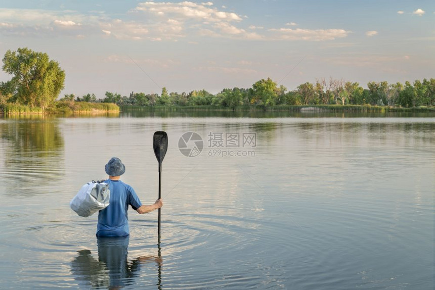 一个男人有条桨和防水的便衣腰部深水周围没有船或桨板图片