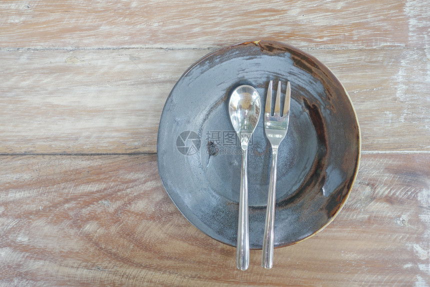 木制桌上配有勺子和叉的平板图片