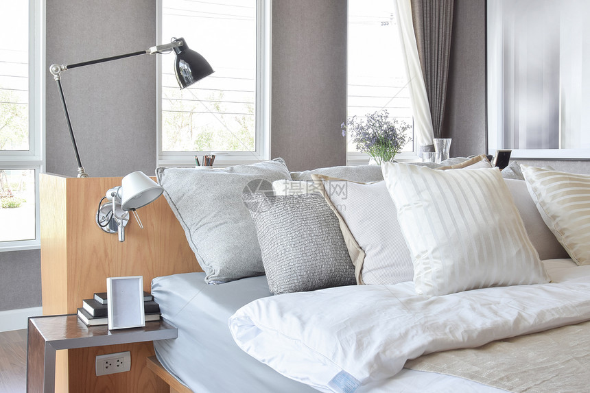 时髦的卧室内设计床边有白条纹枕头和装饰桌灯图片