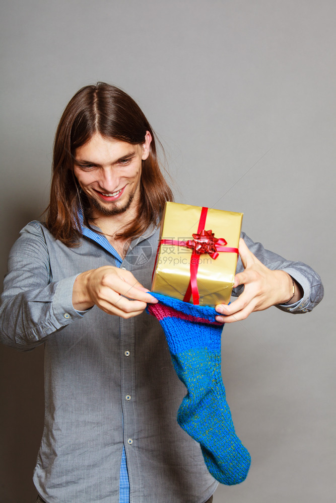 时节圣诞季日冬时髦的人把包装礼物放在编织圣诞节袜子里人把包装的礼物放在编织圣诞节袜子里图片