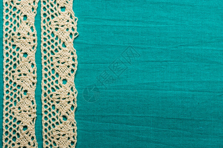 用于庆祝邀请的复选边界绿色蓝纺织品背景的旧白色带子上覆绿蓝纺织品背景图片