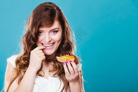 紧贴着笑可爱的卷发女人手拿着水果蛋糕图片