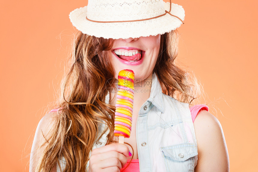 暑假快乐概念有趣的快乐女人蒙着眼睛戴草帽吃了冰淇淋橙色背景的冰淇淋图片