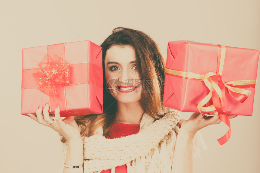 身着红色礼服温暖的羊毛披肩年轻女子拿着两个带丝的礼物盒圣诞节庆祝活动的概念妇女拿着红色圣诞礼物盒图片