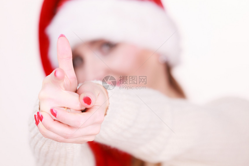 穿着圣塔帽的年轻女士用手指着节假日庆祝休闲时尚概念图片