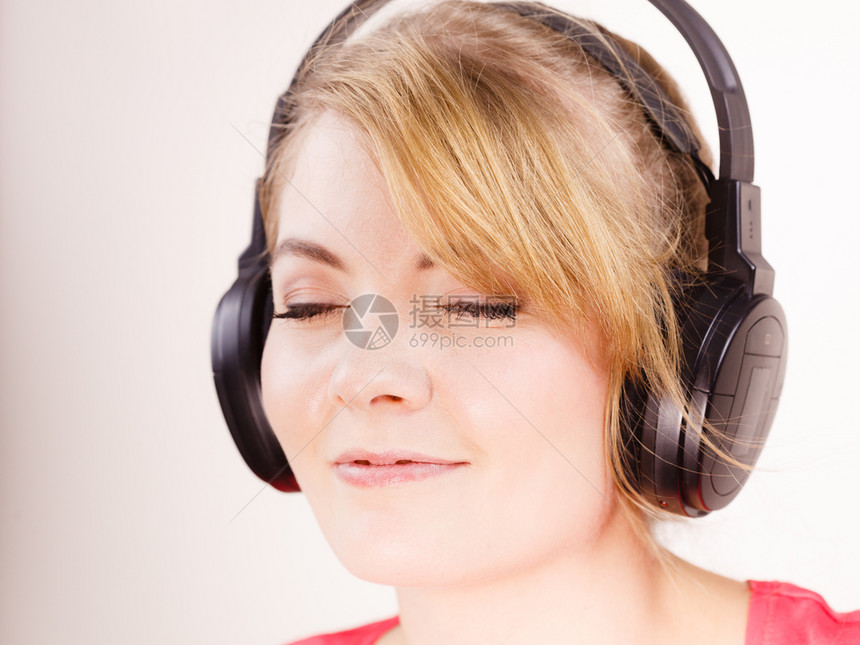 妇女面对大耳机听到音乐mp3微笑的女模范人们享受快乐的概念大耳机中的女人听音乐图片