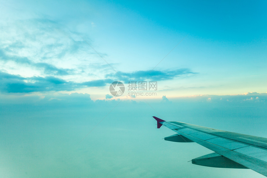 旅客在飞机窗玻璃前拍摄日出图片