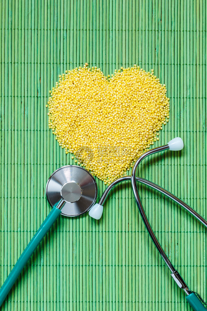健美的生活概念小米呻吟心脏形状和听诊器在绿垫表面健康食物帮助降低胆固醇图片