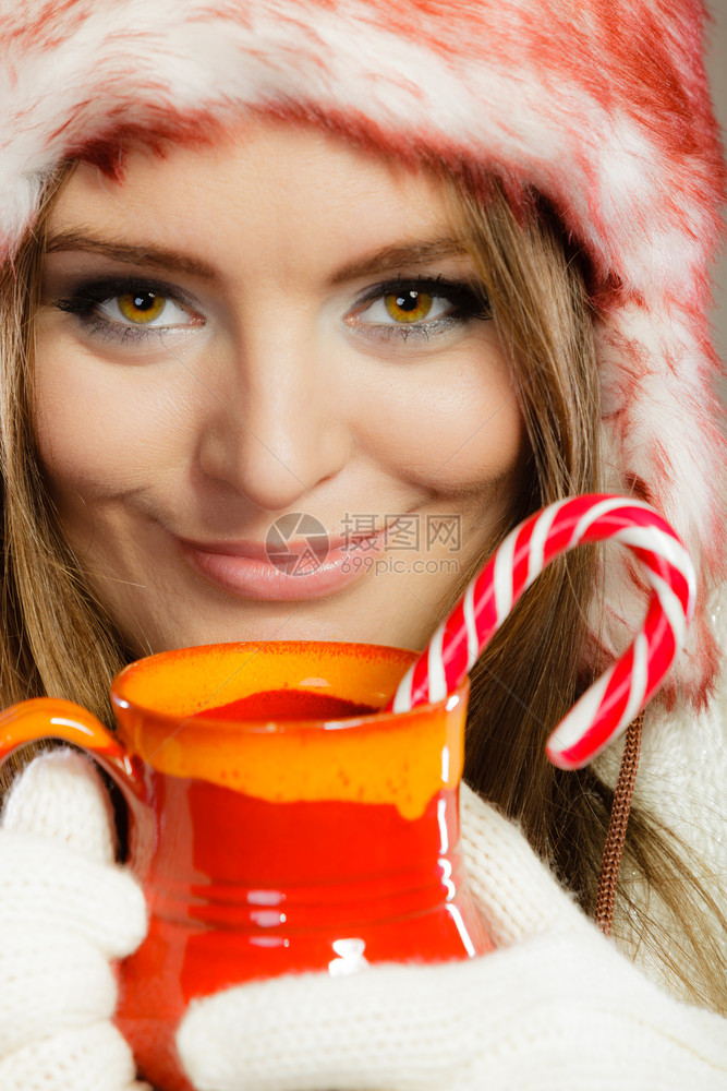 穿着冬装的女人拿红杯喝热饮和条纹的甘蔗图片