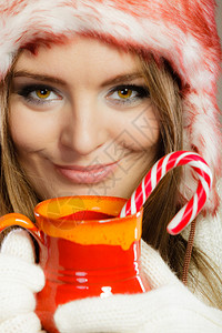 穿着冬装的女人拿红杯喝热饮和条纹的甘蔗图片