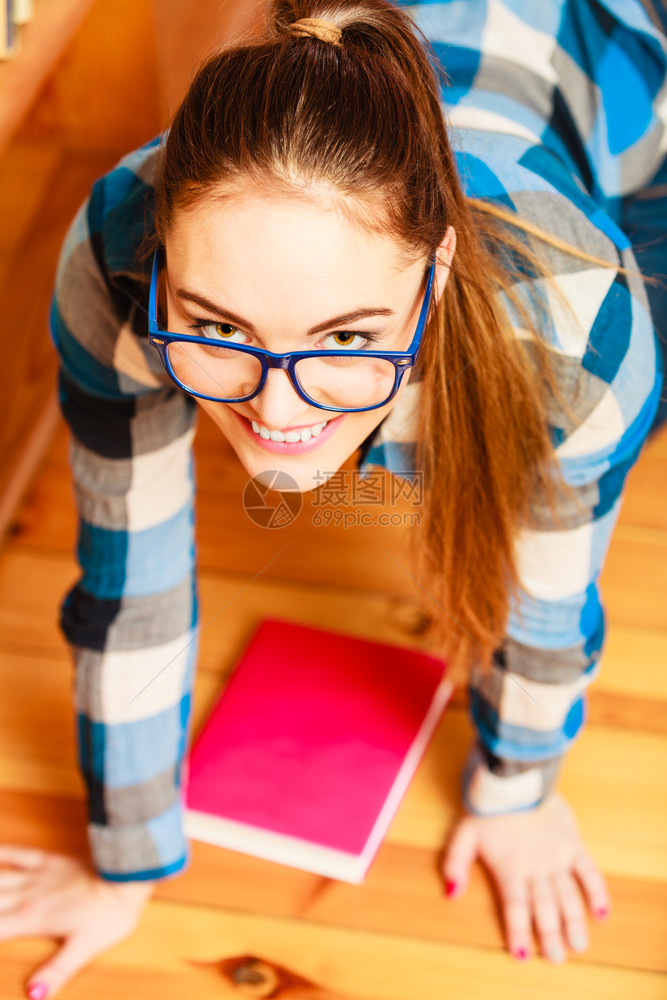 学校教育概念女生时髦穿着蓝眼镜在地板上做马尾辫背书阅读图片