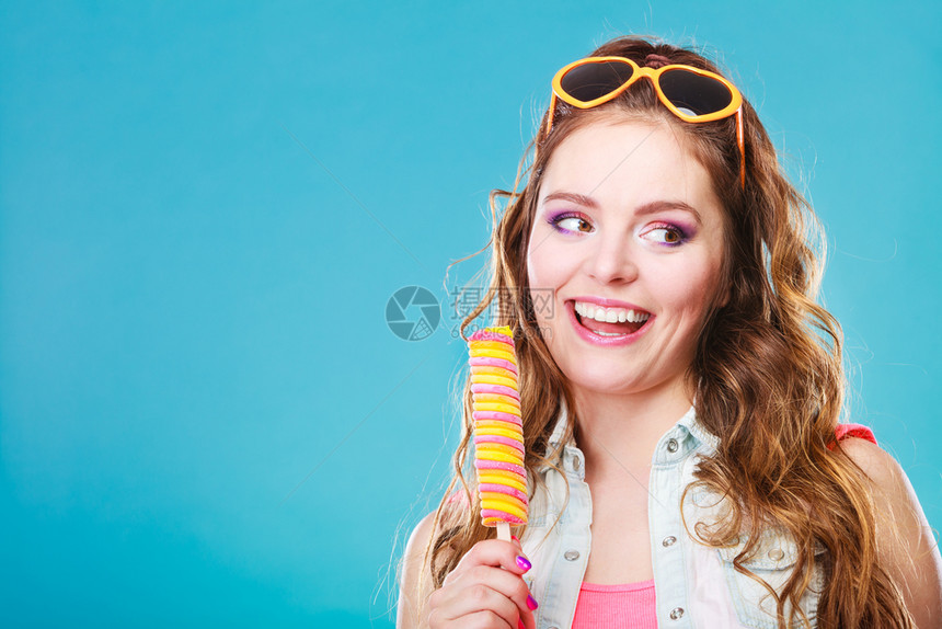 快乐的年轻女模特蓝底吃冰图片