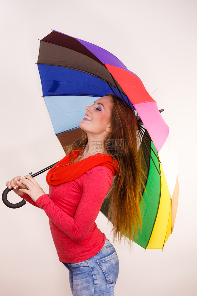 穿着红衣站在多彩雨伞下玩乐的时装髦笑脸的女孩气象预报和天季节概念妇女在多彩雨伞下站立图片