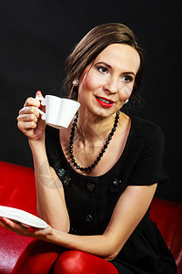 喝咖啡的时间到了女人的古老风格高雅的女士喝茶杯热饮坐在红沙发上室内图片