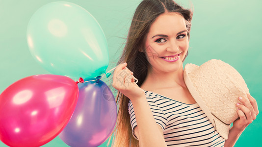 快乐和夏天年轻有魅力的快乐女人戴着草帽满身多彩的气球绿色背景玩彩气球的快乐女孩背景图片