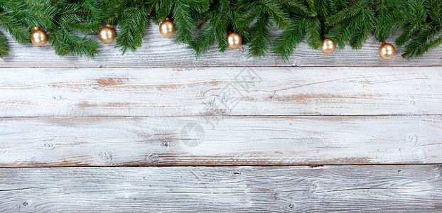 圣诞长绿树枝和白旧木上金首饰的顶端边界图片