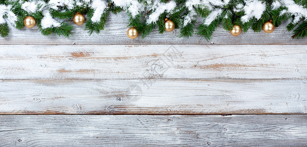 雪的顶端边界覆盖了圣诞常青树枝和白旧木的金饰品图片