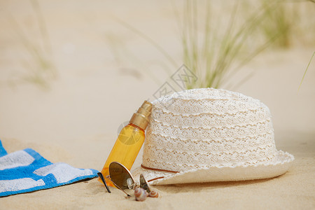 沙滩上放夏帽太阳墨镜和沙滩上的润肤液图片