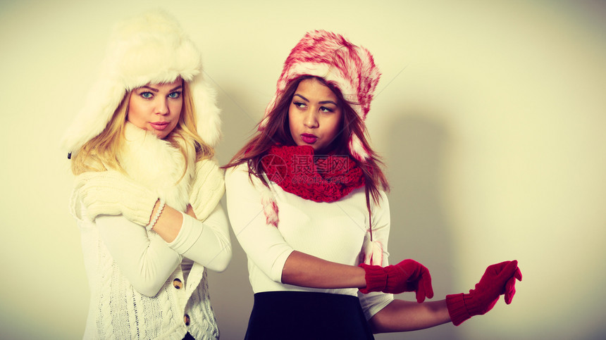 时装冬季饰概念两个金发女孩和黑穿着温暖的红色白服装肖像两个穿着毛帽围巾手套的迷人女两个穿着温暖的冬季服装肖像女孩图片