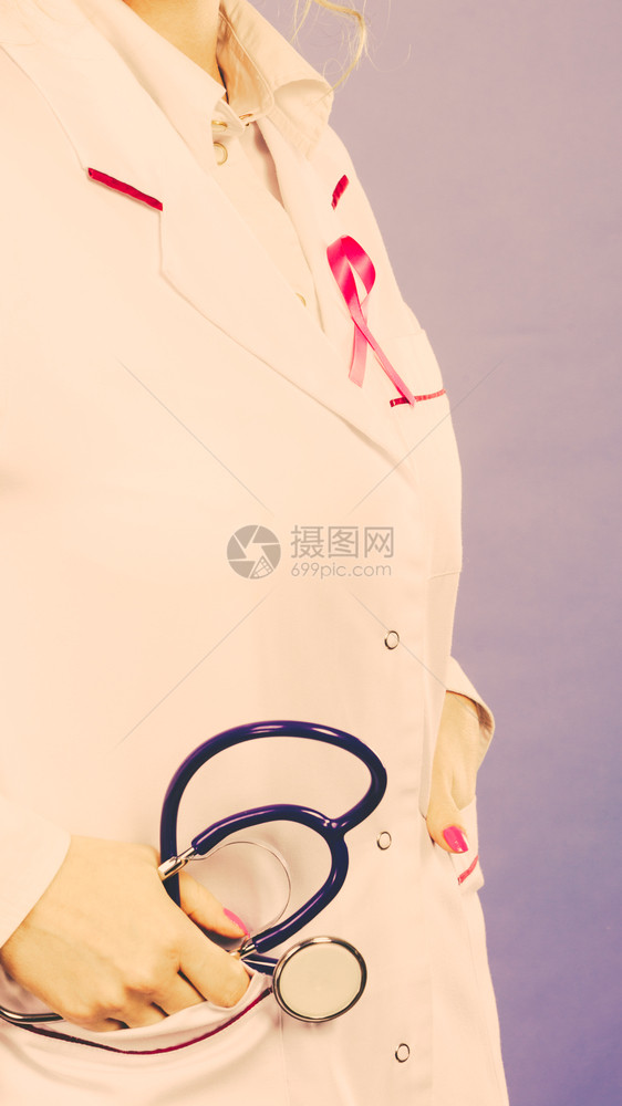 妇女为健康而斗争乳腺癌肿瘤概念白色医疗围裙制服上的粉色丝带和口袋中的蓝色听诊器穿医疗制服的粉色丝带和听诊器图片