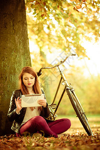 大自然户外概念年轻女士在玩平板电脑美丽的女士坐在树下图片