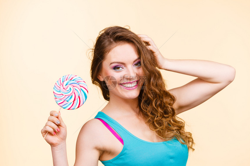 美貌丽的女孩手拿着多彩的棒糖玩得开心甜食和幸福的概念工作室拍摄在明亮的背景上带棒糖的女人快乐孩图片