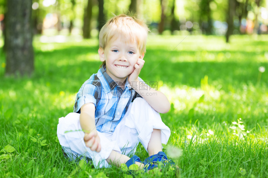 一个小男孩在草地上看着镜头图片
