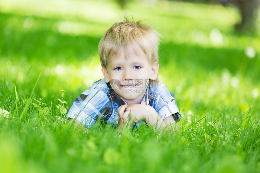 一个小男孩在草地上看着镜头图片
