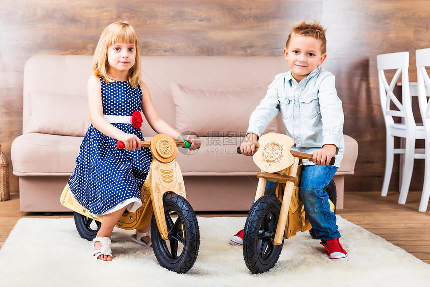 快乐笑的小孩在客厅家中骑木自行车图片