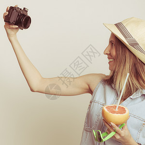 穿着草帽的观光女乘着摄影机拍自同时手握葡萄水果图片