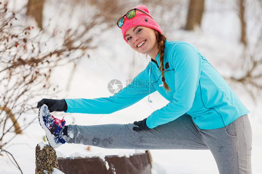 年轻女孩穿着运动服在雪地里拉伸图片