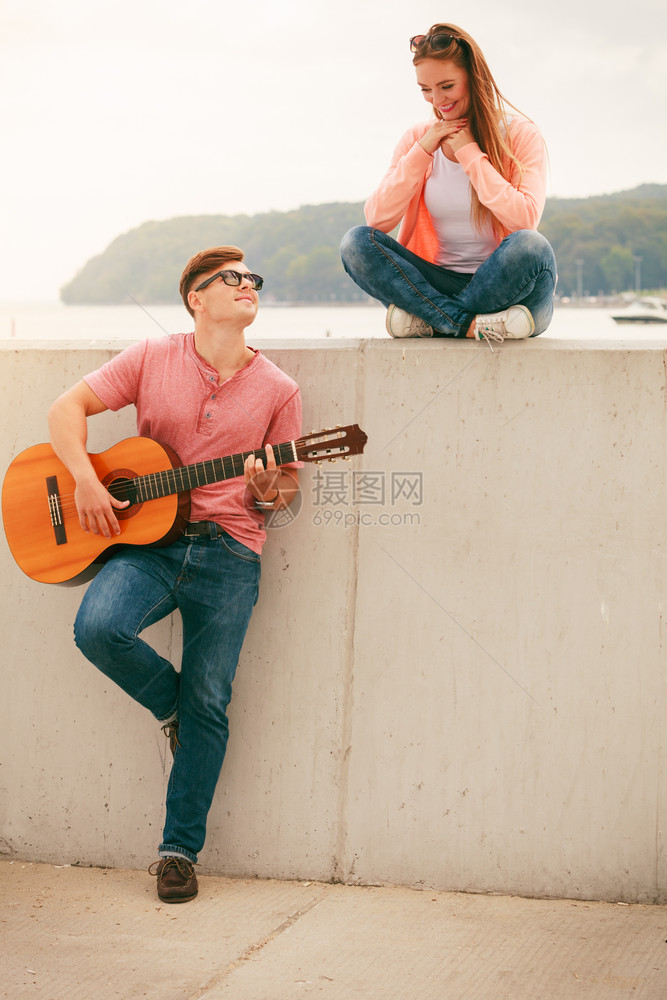 乐器和音概念器和玩的年轻情侣玩经典吉他的人在海上户外约会图片