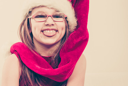 戴圣诞帽子的托德勒女孩穿着圣诞帽子和礼服长着笑脸尖舌的图片