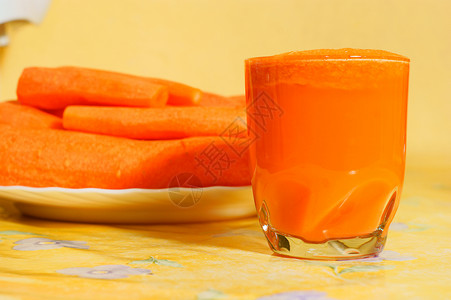玻璃中的胡萝卜果汁黄色背景图片