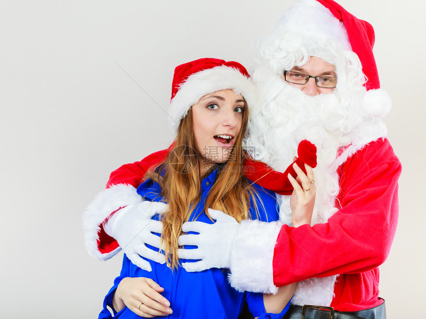 圣诞老人的迷女士穿着红色帽子和蓝服装的漂亮女人和圣诞老的图片