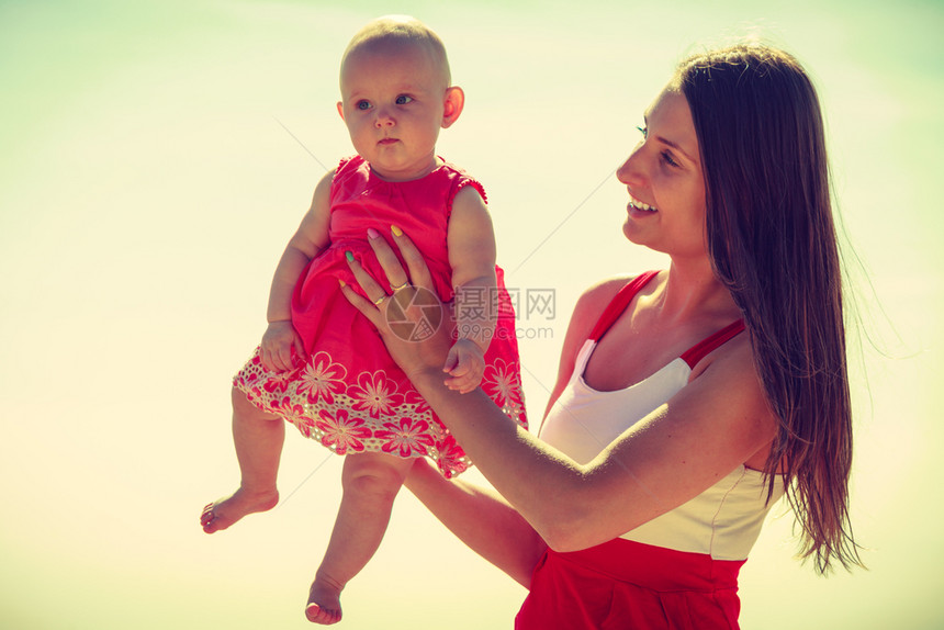 母亲和女婴在靠近海边的滩上度过时间图片