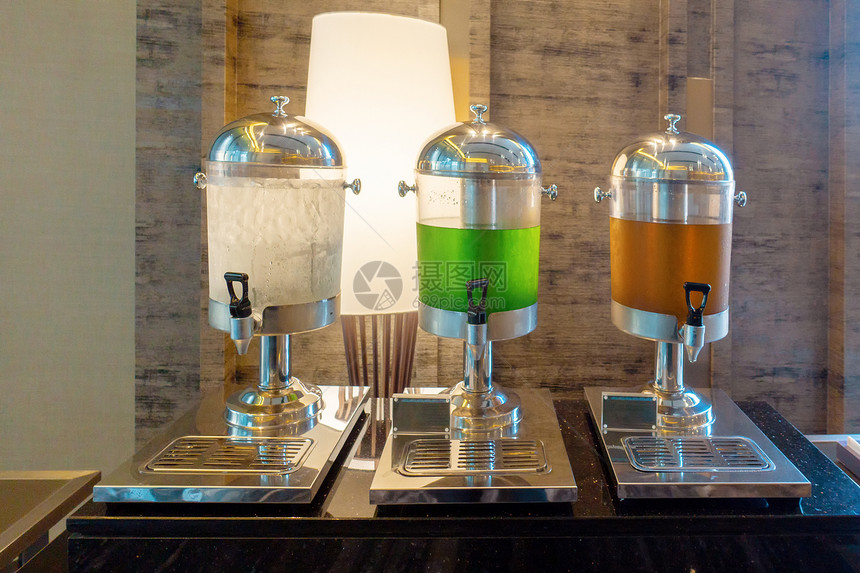 饮用水瓜瓦和橙汁在水冷却器中供早餐酒吧自我服务研讨会的客人使用图片