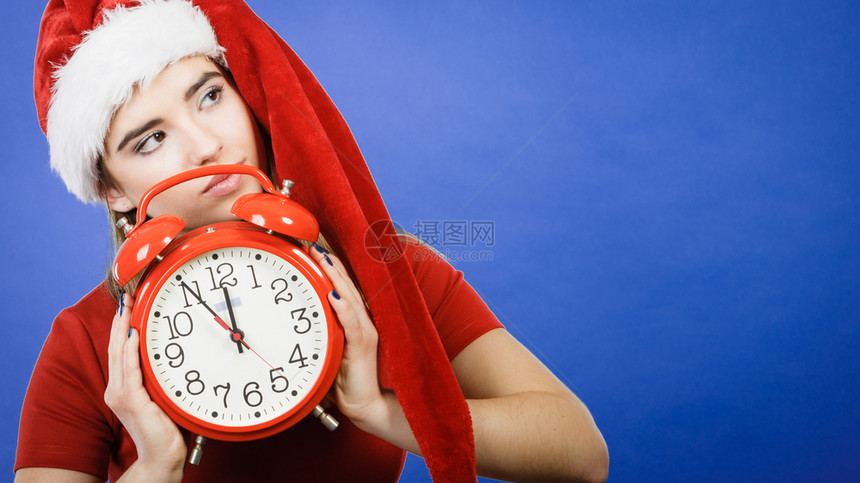 穿着圣诞老人帮手服装的妇女穿着圣诞老人的服装穿着红色大钟等庆祝图片