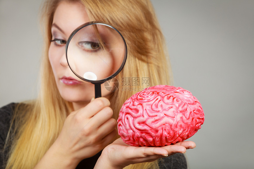 金发女人拿着放大镜调查某事仔细观察假大脑图片