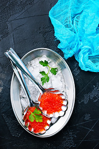金属托盘上的勺中红鲑鱼子酱背景图片