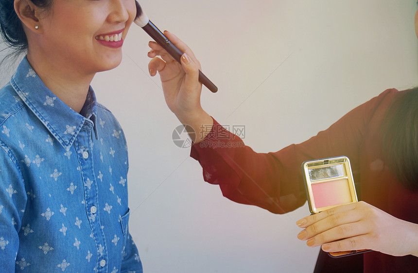 专业化妆师用脸红粉与美丽的亚洲女合作图片