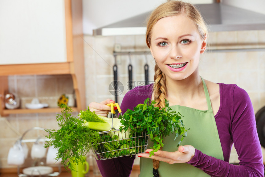购买健康的饮食品概念厨房里的妇女有许多绿色蔬菜手持小购物篮厨房里的妇女手持蔬菜厨房里的妇女手持蔬菜篮子图片
