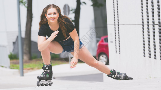 身穿溜冰鞋的妇女在城里骑马女运动家在长途旅行前伸展腿部图片