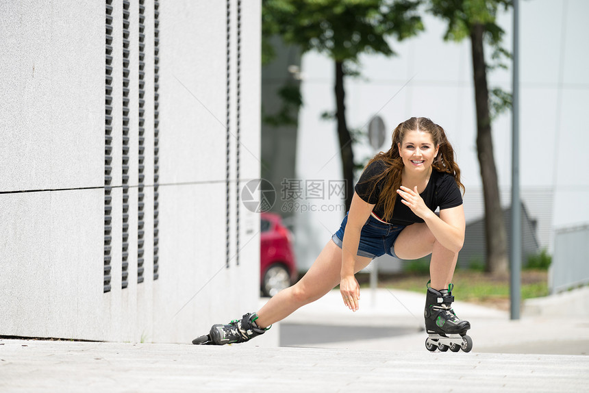 身穿溜冰鞋的妇女在城里骑马女运动家在长途旅行前伸展腿部图片