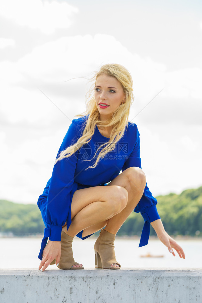 时装女穿蓝色短裤的时装女夏季穿的完美模特户外照片拍摄女装坐在码头放松时装模特穿着蓝色时装图片