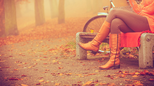 在公园里骑自行车的女士坐在长椅上享受自然女孩坐在秋天公园的长凳上图片