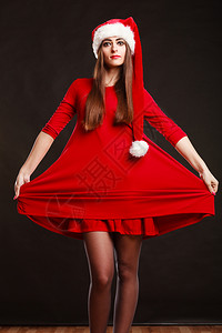 圣诞时间年轻女人穿着黑背景的红礼服穿着圣达克萨斯帽子工作室拍到的图片