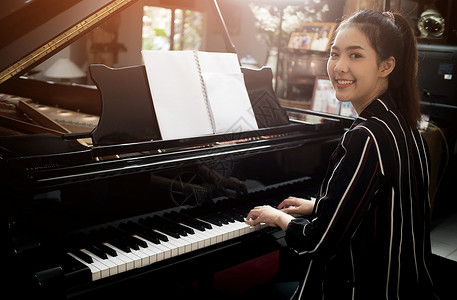 弹钢琴的女孩黑色美丽的亚洲女孩学会弹钢琴背景