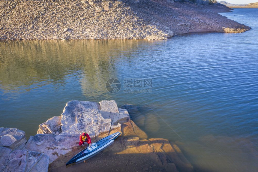 身穿干衣的男板身穿干衣站在山湖的岩石岸上滑板空中视角图片