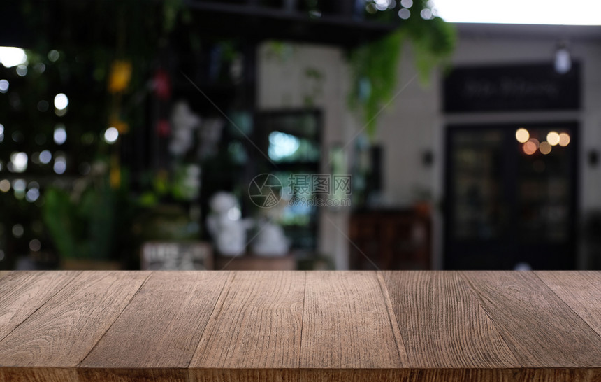 在餐厅的抽象模糊布基背景面前的空暗黑木桌可以用于显示或蒙合您的产品图片
